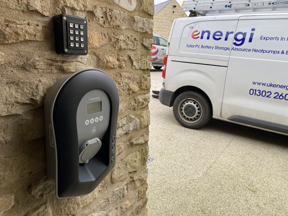 MyEnergi Zappi charger on a sandstone wall with a UK Energi liveried van in the background